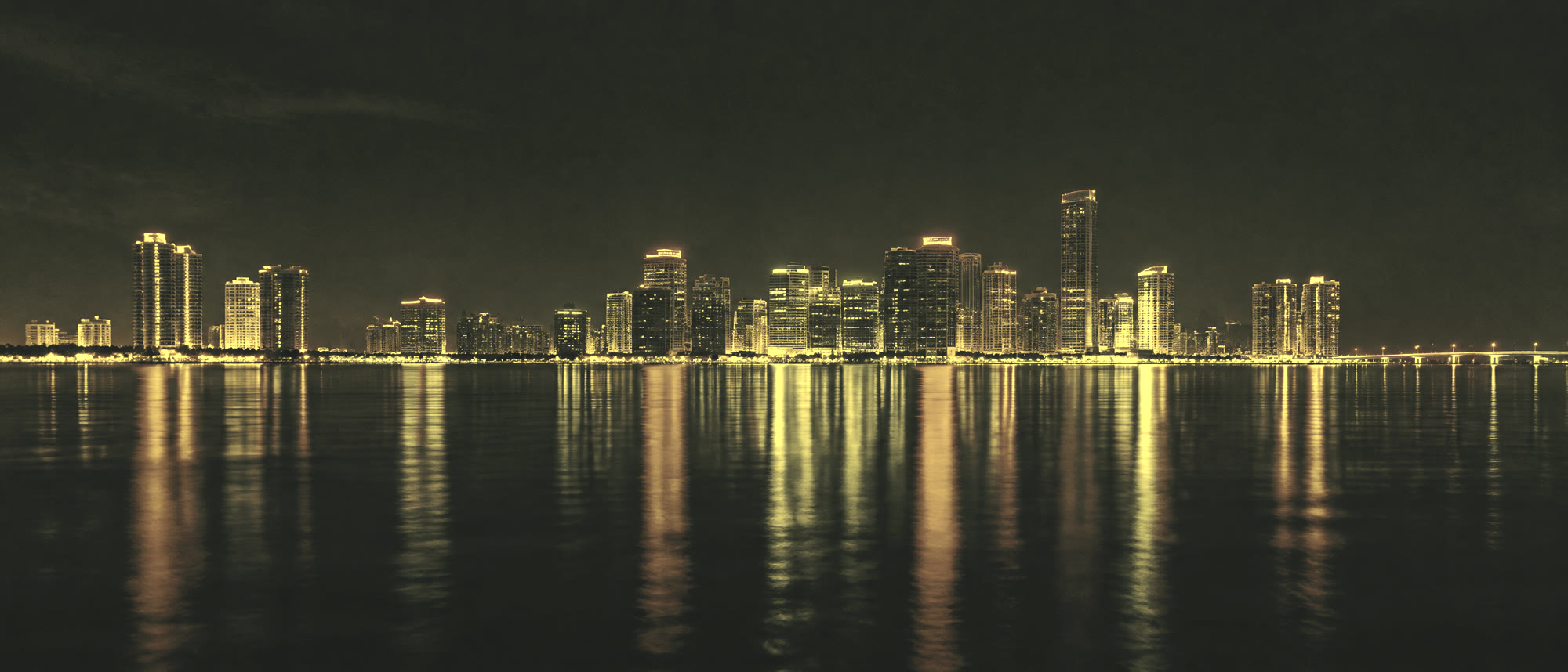 City lights along a waterfront at night, reflected in still water